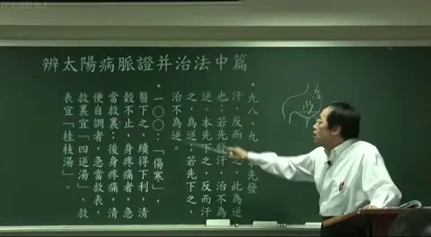  黑板板书特写，讲者手指指向第“一〇〇”条文：“伤寒，医下之，续得下利，清谷不止...”，讲解伤寒误下的急救顺序。